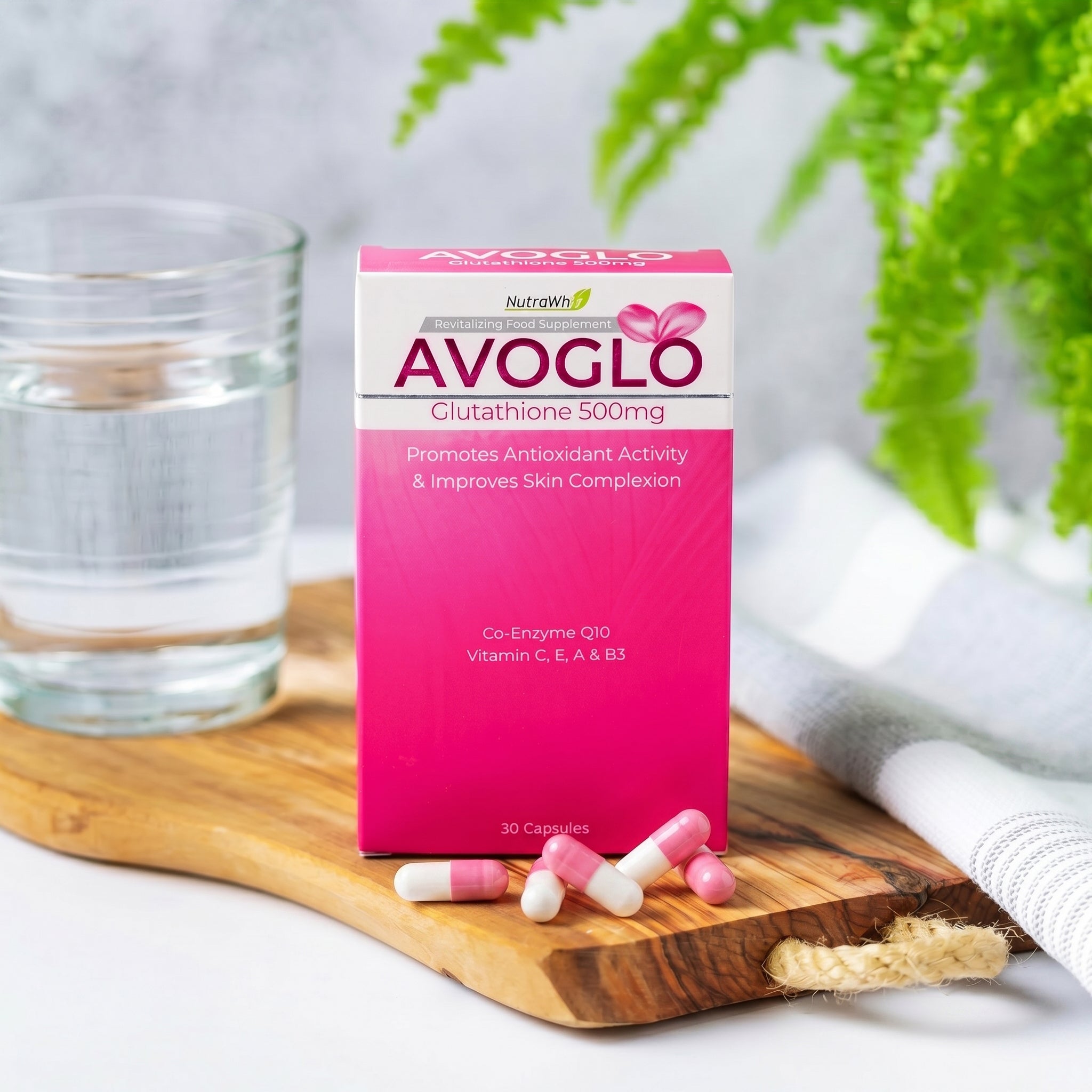AVOGLO Glutathione 500mg capsules box and loose capsules on a wooden board next to a glass of water
