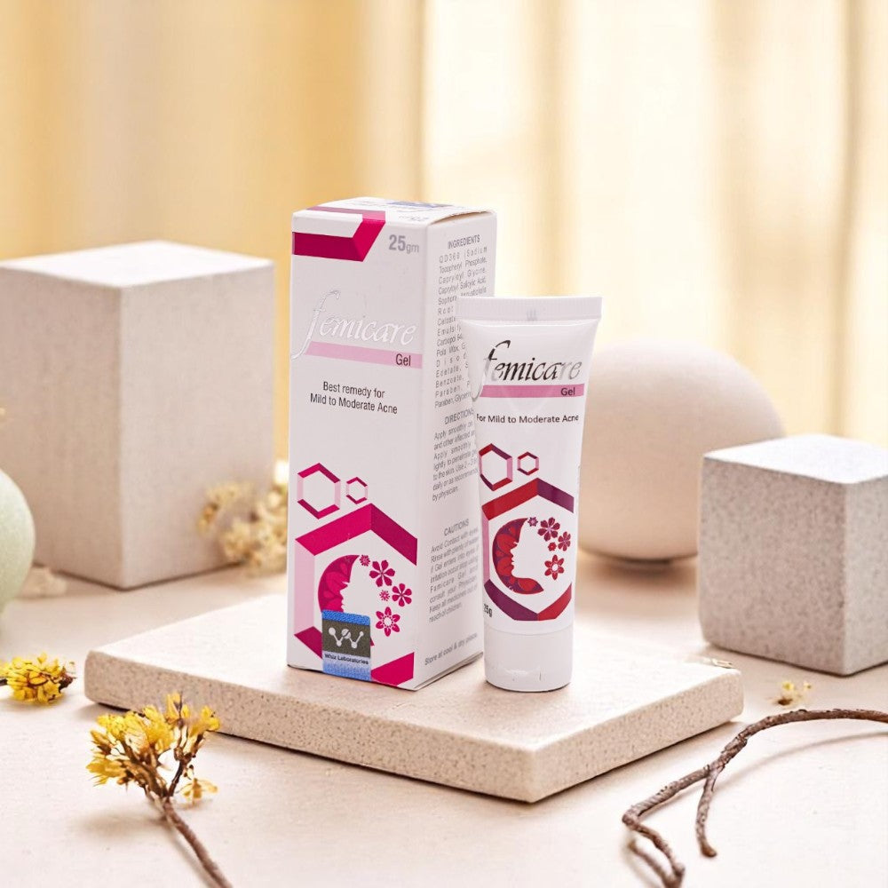 Femicare Acne Gel, 25g tube and its white and pink box, set among light-colored decorative blocks and dried flowers.