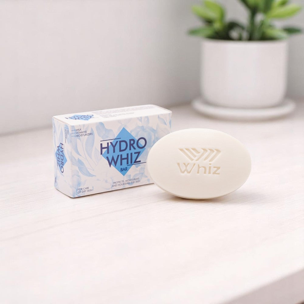 Hydro Whiz Bar, an oval-shaped white soap bar with 'Whiz' embossed on it, and its white and blue box with a leafy pattern, set on a white wooden surface with a small potted plant in the background.