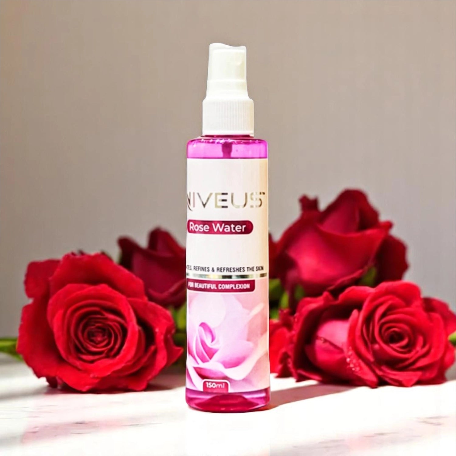 Niveus Rose Water, 150ml pink spray bottle with a white nozzle, surrounded by several red roses.