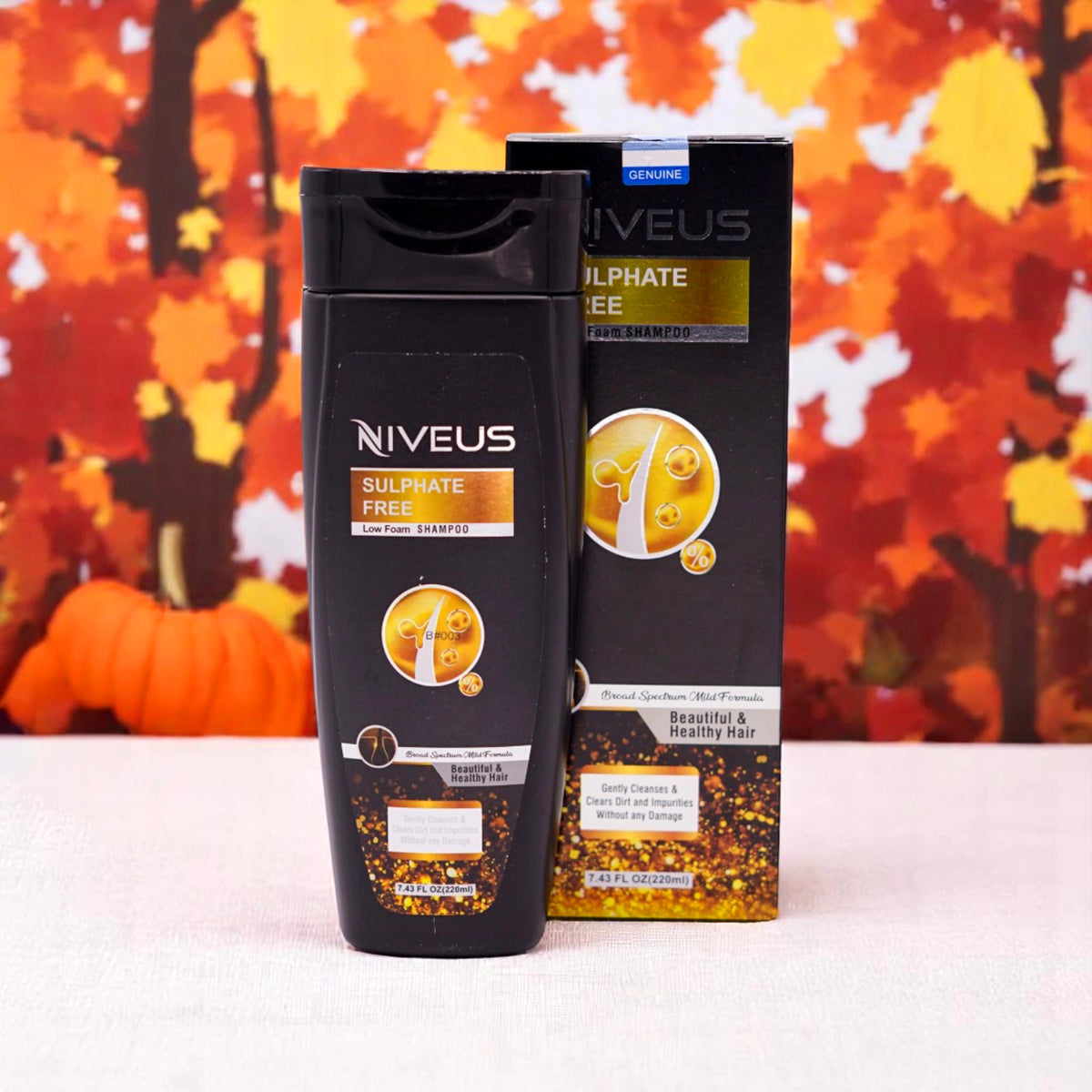 Niveus Sulphate Free Low Foaming Shampoo, 200ml black bottle and its black box with gold accents, set against an autumn-themed background with orange leaves and a small pumpkin.