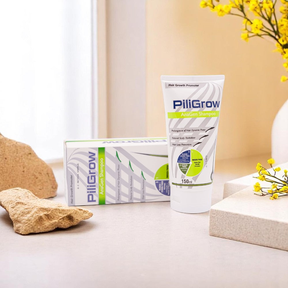 PiliGrow Anagen Shampoo, 150ml tube and its white and green box, set against a background of green leaves and yellow flowers.