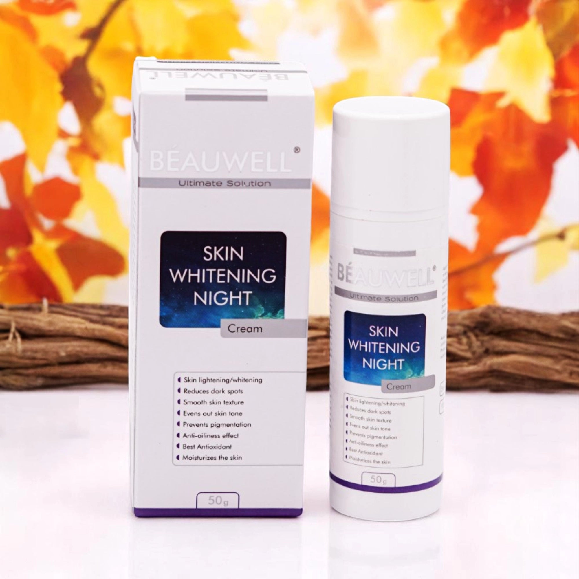 Beauwell Ultimate Solution Skin Whitening Night Cream, 30g white pump bottle and its matching white box with purple accents, set against a blurred background of autumn foliage.