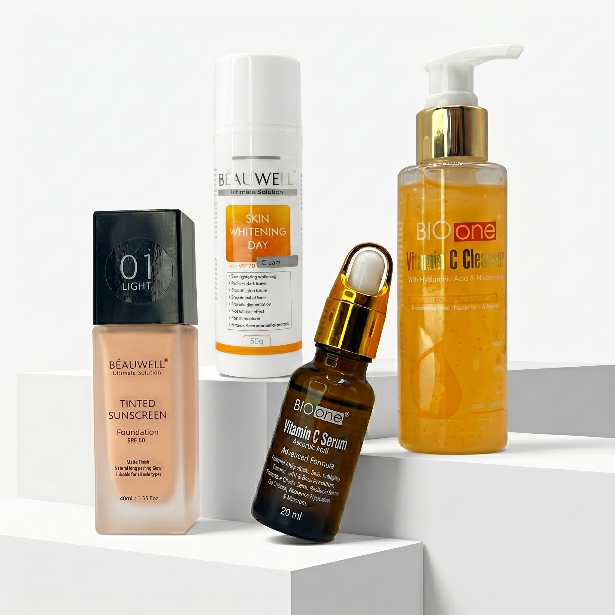 Whiz Brightening Bundle featuring Bio One Vitamin C Cleanser, Vitamin C Serum, Beauwell Skin Whitening Day Cream, and Tinted Sunscreen on white pedestal blocks.