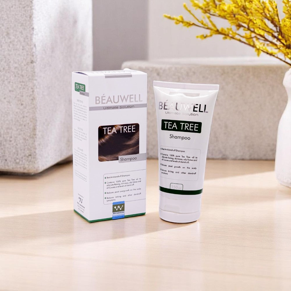 Beauwell Tea Tree Shampoo, 150ml white tube and its white and green box, set among light-colored decorative blocks and yellow flowers.