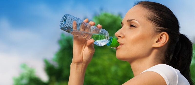 Girl is drinking water from bottle that help in skin moisturizing