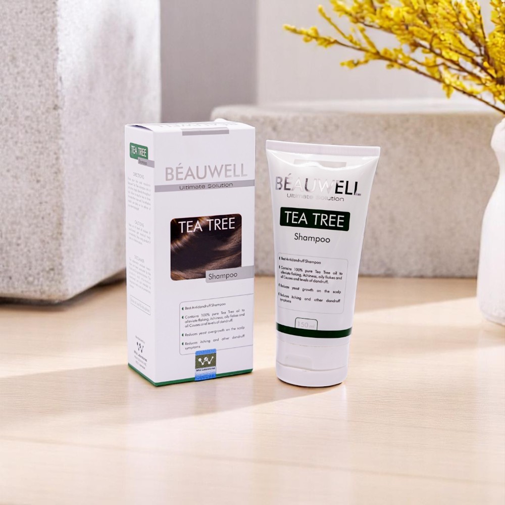 Beauwell Tea Tree Shampoo, 150ml white tube and its white and green box, set among light-colored decorative blocks and yellow flowers.